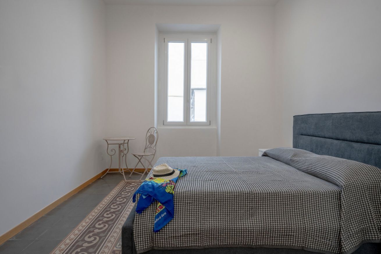 Une chambre à coucher avec un lit, une fenêtre, une chaise et une petite table.