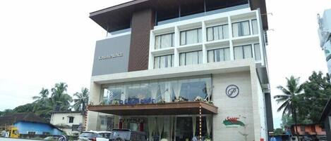 A modern hotel with a prominent sign, a covered entrance, and a parking area.