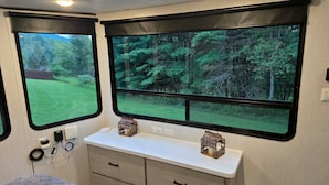 A bedroom with a large window, a bedside table, and a bed.
