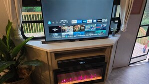 A flat-screen TV on a wooden stand with a fireplace below it.