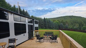 A deck with outdoor furniture and a view of a forested hill.