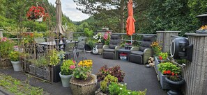 An outdoor patio with a dining table, chairs, and a seating area. There are potted plants and a bird feeder. - Cozy vacation apartment near Nürburgring for 2 people (Welschenbach)