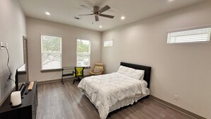 Ein Schlafzimmer mit Bett, Schreibtisch, Stuhl und Deckenventilator.