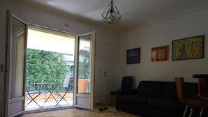 An open sliding door leading to a balcony with a metal railing, a black sofa, and a chair in the living area. - Enchanting apartment with AC in Cannes (Cannes)