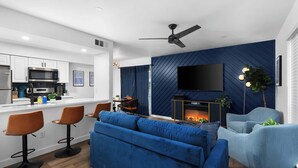 Un salon moderne avec un canapé bleu, un téléviseur à écran plat fixé au mur et une cheminée.