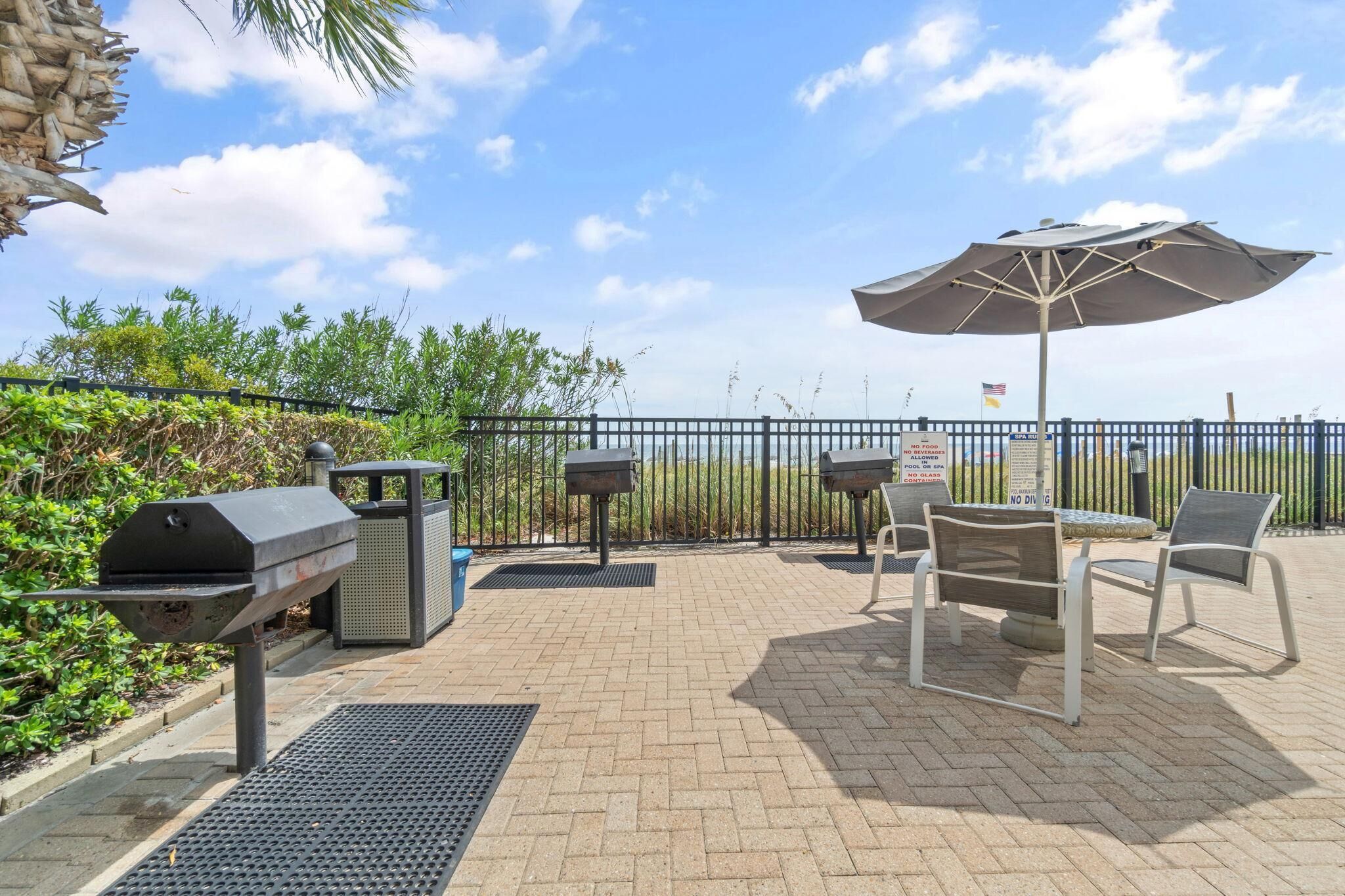 Une terrasse extérieure équipée d’un barbecue, de sièges et offrant une vue sur l’océan.