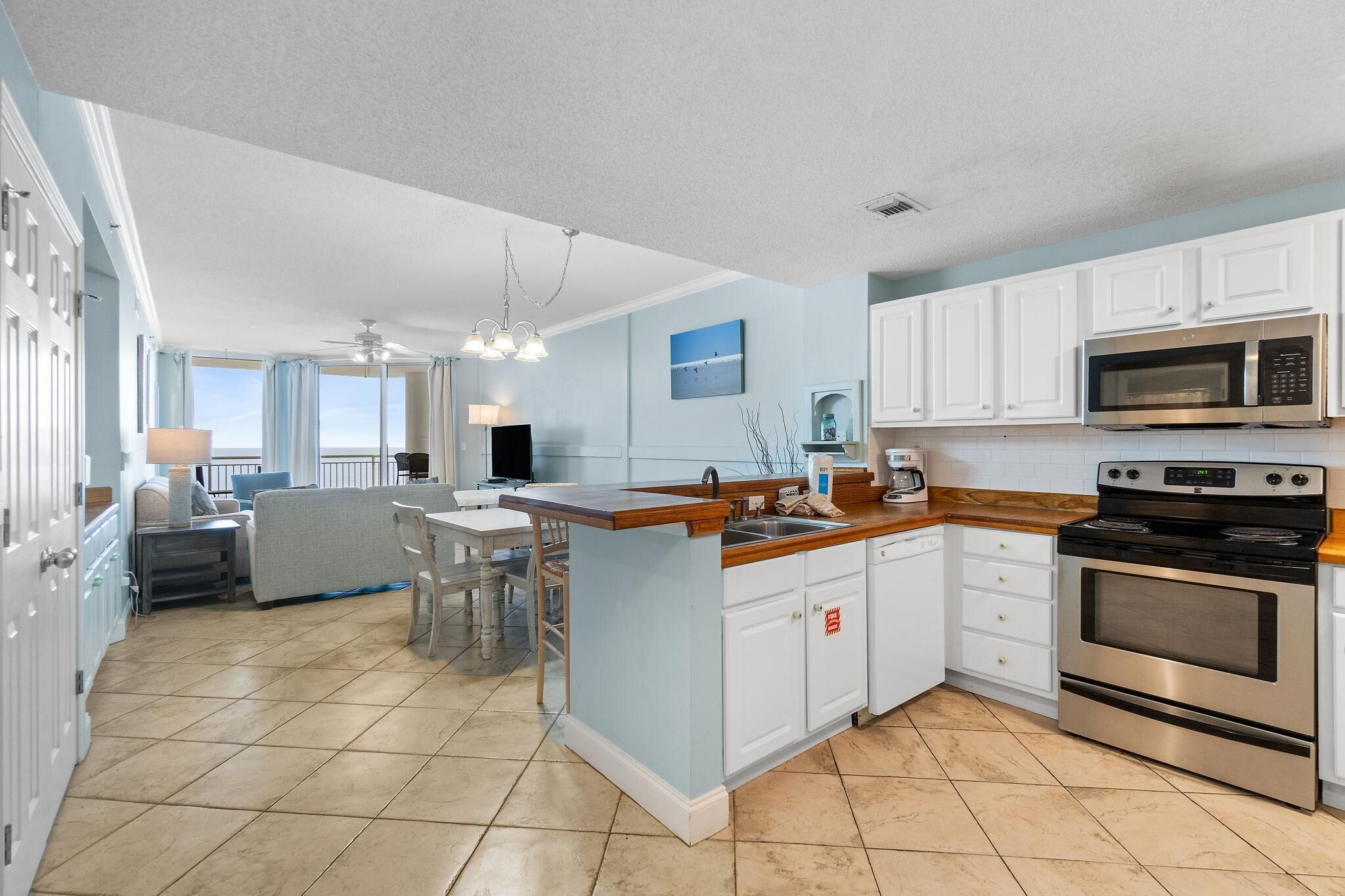 A spacious kitchen with a large island, white cabinets, a microwave, and an oven.