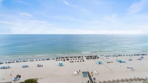 A beach with rows of blue and white umbrellas, a sandy shore, and a clear sky. - Palacio 802 (Pensacola)
