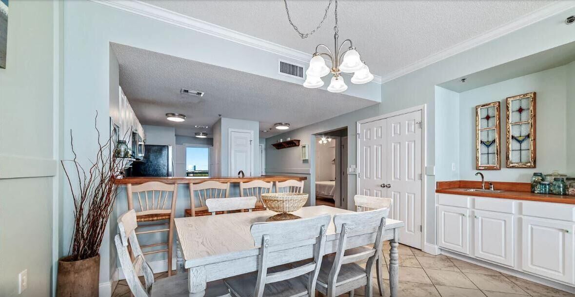 A modern kitchen with white cabinetry, a central island with seating, and a chandelier.