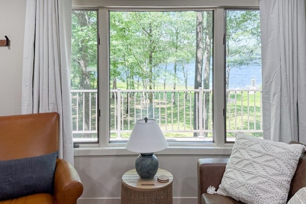 Peaceful lake view from the comfort of your living room, framed by large windows that invite the beauty of Deep Lake indoors.