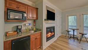 A kitchen with wooden cabinets, a microwave, a coffee maker, and a fireplace. - Riverside Trout Cottage / Sleeps 8 / Short walk to Downtown Helen (Helen)