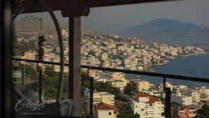 A view from a window overlooking a coastal cityscape with buildings and a mountain in the background. - Angel Saranda Palace (Sarande)