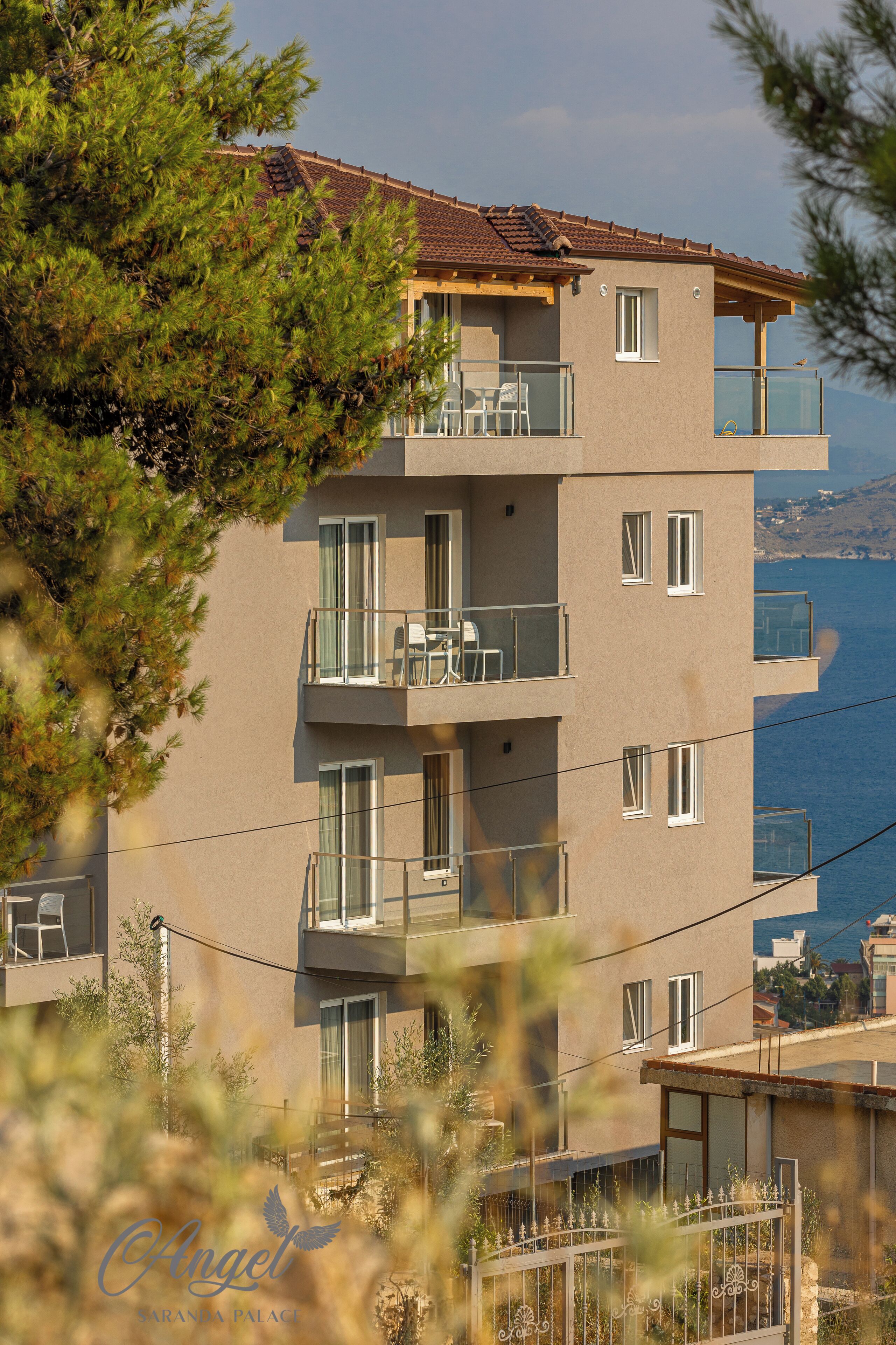 Un immeuble à plusieurs étages, doté de balcons, offrant une vue sur la mer et s’ouvrant sur un ciel dégagé.