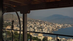 A view from a window overlooking a coastal cityscape with buildings and a mountain in the background. - Angel Saranda Palace (Sarande)