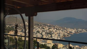 Vista desde una ventana hacia un paisaje urbano costero con edificios y una montaña al fondo.