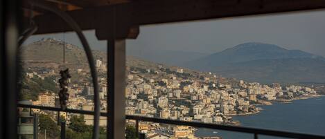 A view from a window overlooking a coastal cityscape with buildings and a mountain in the background.