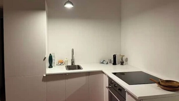 A modern kitchen with white cabinets, a black countertop, a sink, a stove, and a pendant light. - T2 Design - Montpellier Centre (Montpellier)