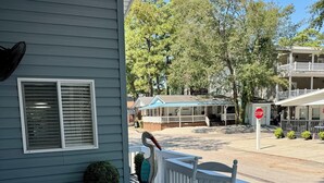 A covered porch with wicker furniture and a stop sign in the background. - Salty Britches Cottage, with Golf Cart in Ocean Lakes! (Myrtle Beach)