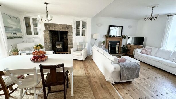 A living room with a fireplace, white furniture, and a television.