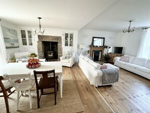 Un salon avec une cheminée, des meubles blancs et un téléviseur.