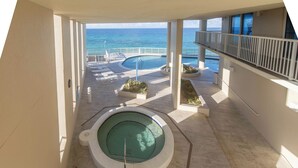 A pool area with a hot tub, lounge chairs, and a view of the ocean. - Coastal Escape West - Unit 506, beach service inc., 1 mile West of Pier Park (Panama City Beach)