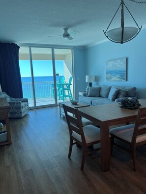Ein Zimmer mit Esstisch, Stühlen, einer Couch, einem Deckenventilator und Meerblick durch eine Schiebeglastür.