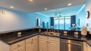A modern kitchen with white cabinets, a black granite countertop, stainless steel appliances, and recessed ceiling lights. - Coastal Escape West - Unit 506, beach service inc., 1 mile West of Pier Park (Panama City Beach)