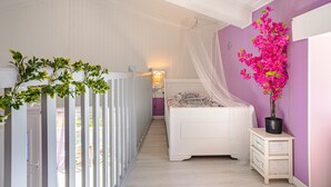 Un dormitorio con cama, mesita de noche, ventana con cortinas y una planta en maceta.