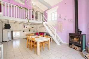 Un espace de vie à plusieurs niveaux comprenant un coin repas, un escalier et un poêle à bois.