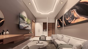 A modern living room with a flat-screen TV, a sofa, a coffee table, and artwork on the walls. - Utkal Hotels Bhubaneswar (Bhubaneshwar)