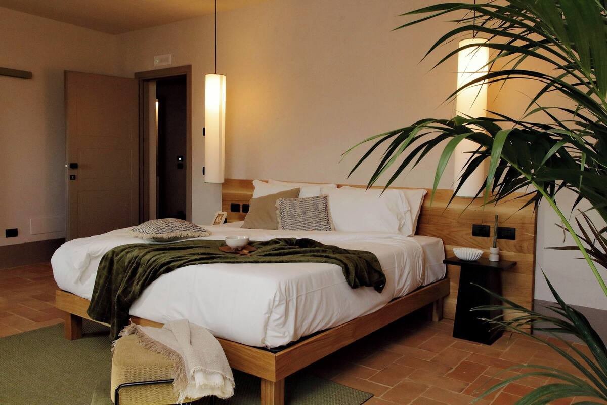 Une chambre à coucher avec un lit en bois, une table de chevet, une lampe et une plante en pot.