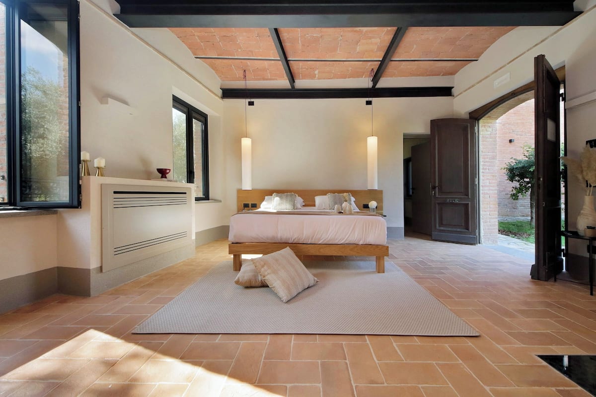 Une chambre avec un grand lit, une table de chevet, un radiateur et une fenêtre.
