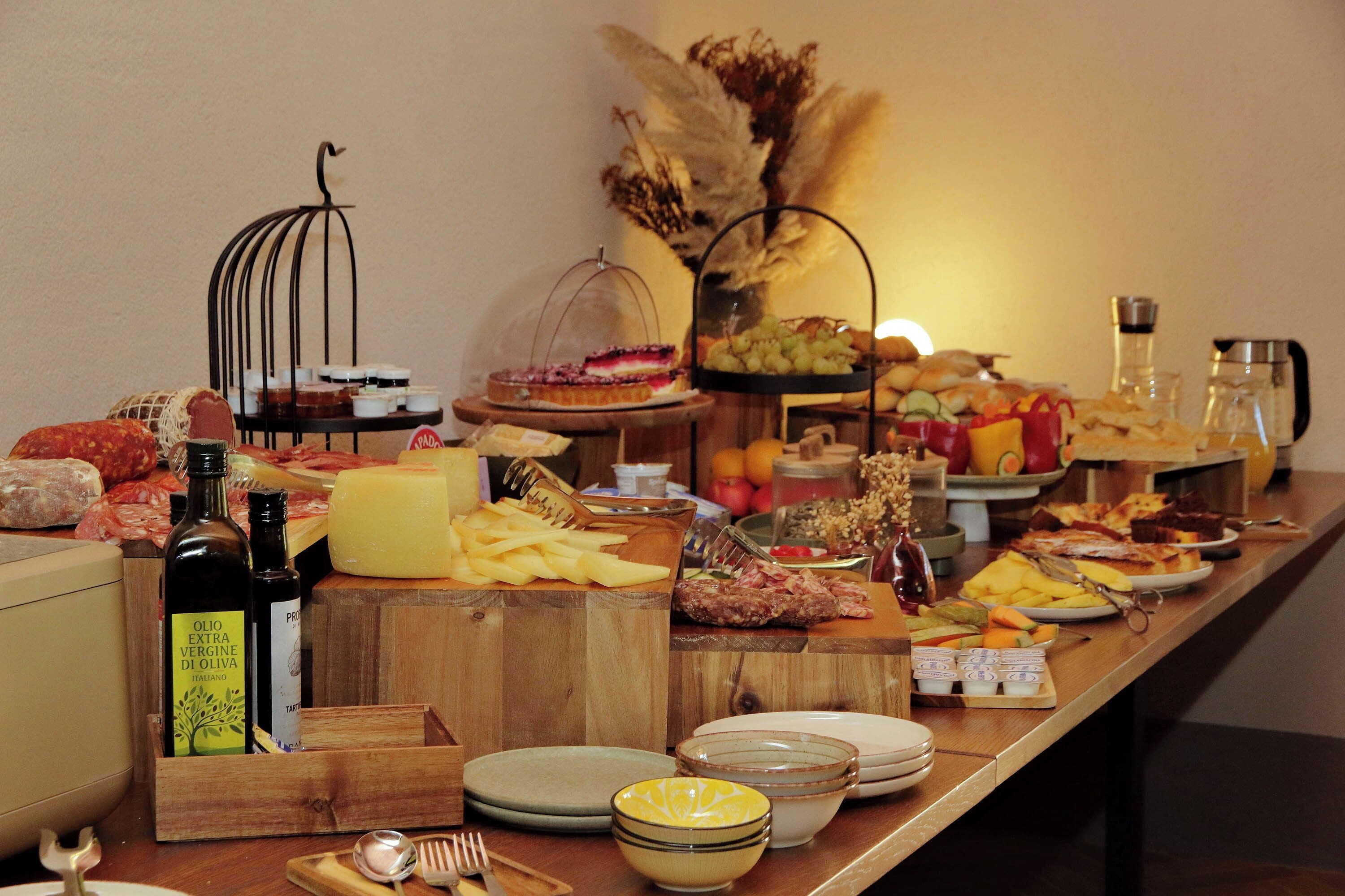 Une table de buffet proposant une variété d’aliments, notamment des fromages, des viandes et des fruits.
