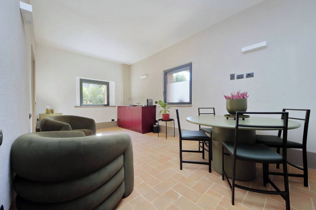 Une cuisine moderne avec un meuble rouge, une table à manger avec des chaises et une plante en pot.
