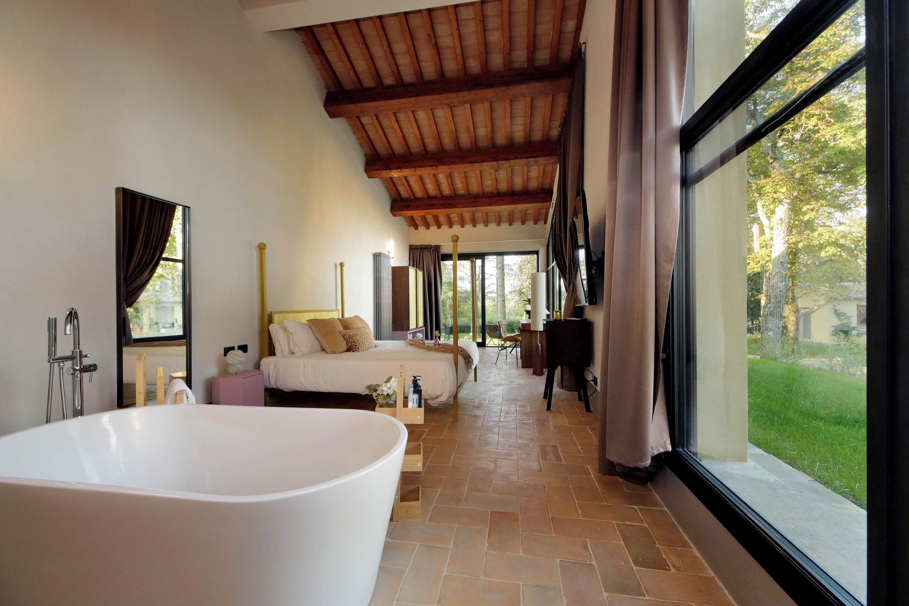 Un baño espacioso con una bañera grande, zona de ducha y ventana con vistas al exterior.