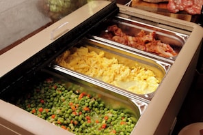 A buffet with various food options including scrambled eggs, bacon, and mixed vegetables.