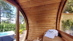 Un sauna en bois avec un jacuzzi à l’extérieur, un banc en bois et une serviette.