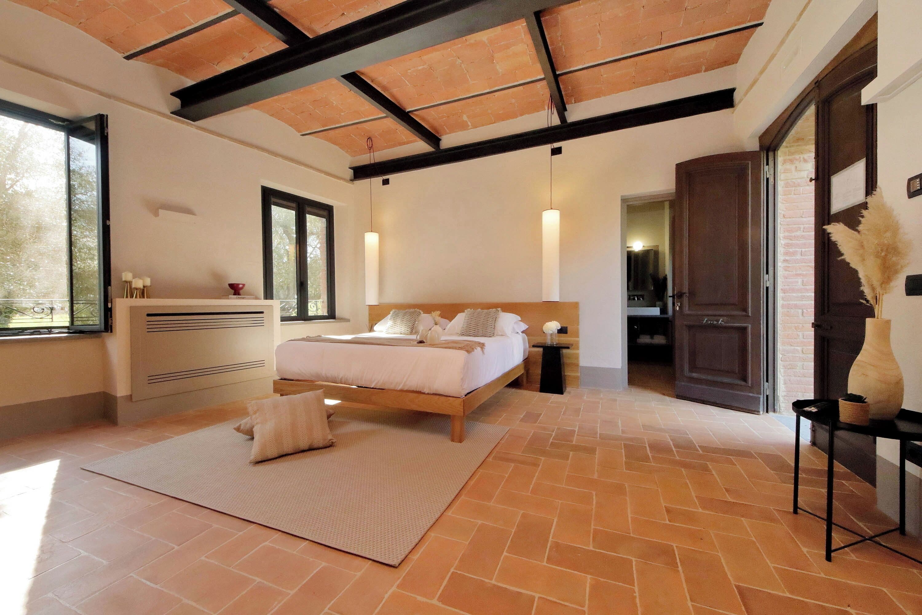 Une chambre à coucher avec un lit, des tables de chevet, une fenêtre et une porte.