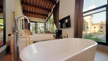 Un dormitorio moderno con una bañera grande, techo de madera y televisor en la pared.
