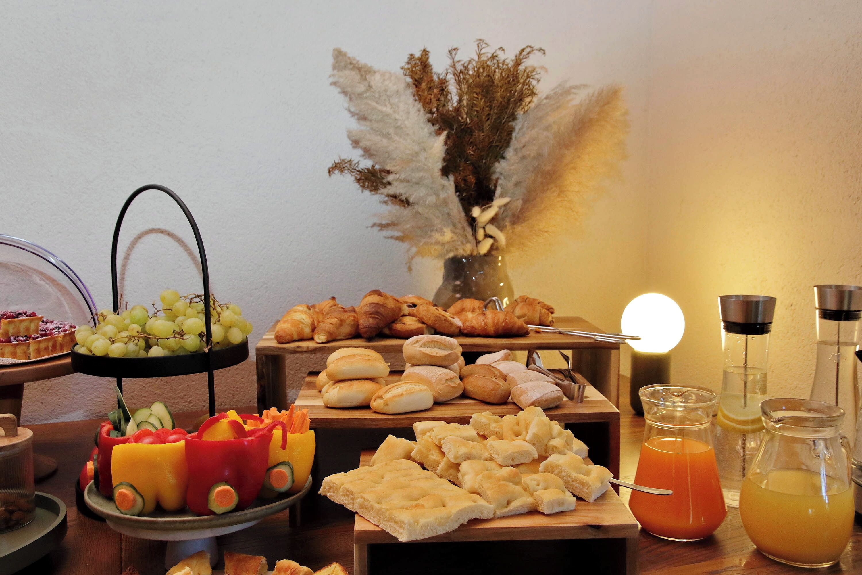 A buffet table with various food items, including bread, pastries, and a fruit arrangement shaped like a car.