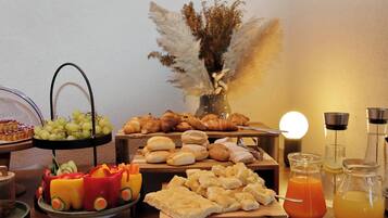 A buffet table with various food items, including bread, pastries, and a fruit arrangement shaped like a car.