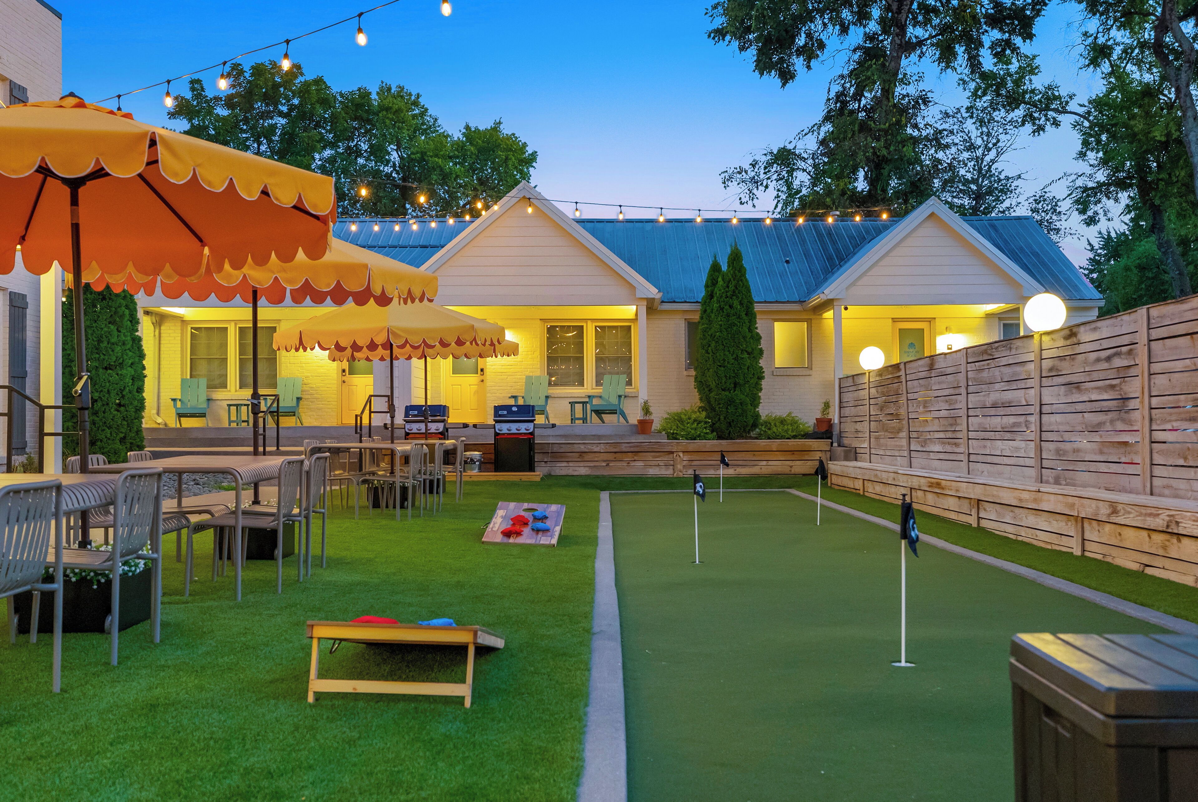 A backyard with a dining area, barbecue setup, and artificial turf.