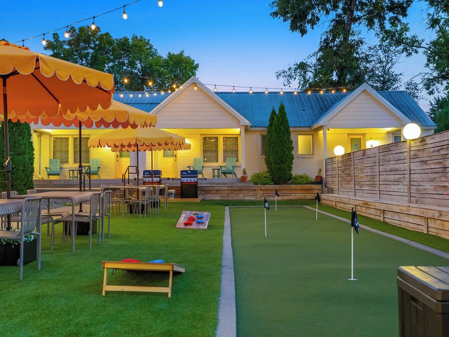 A backyard with a dining area, barbecue setup, and artificial turf.