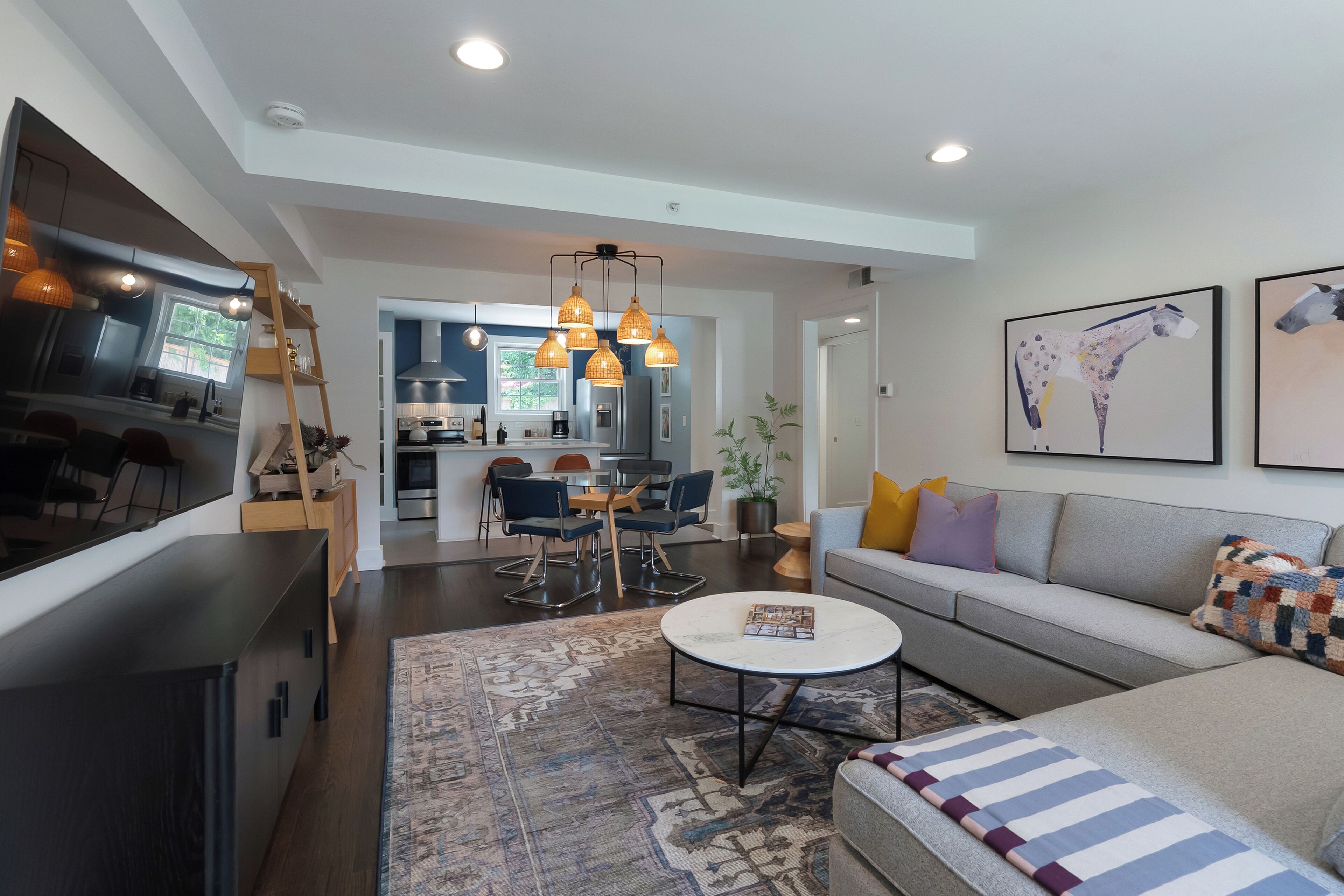 A modern living room with a sofa, coffee table, and a dining area with chairs and a table.