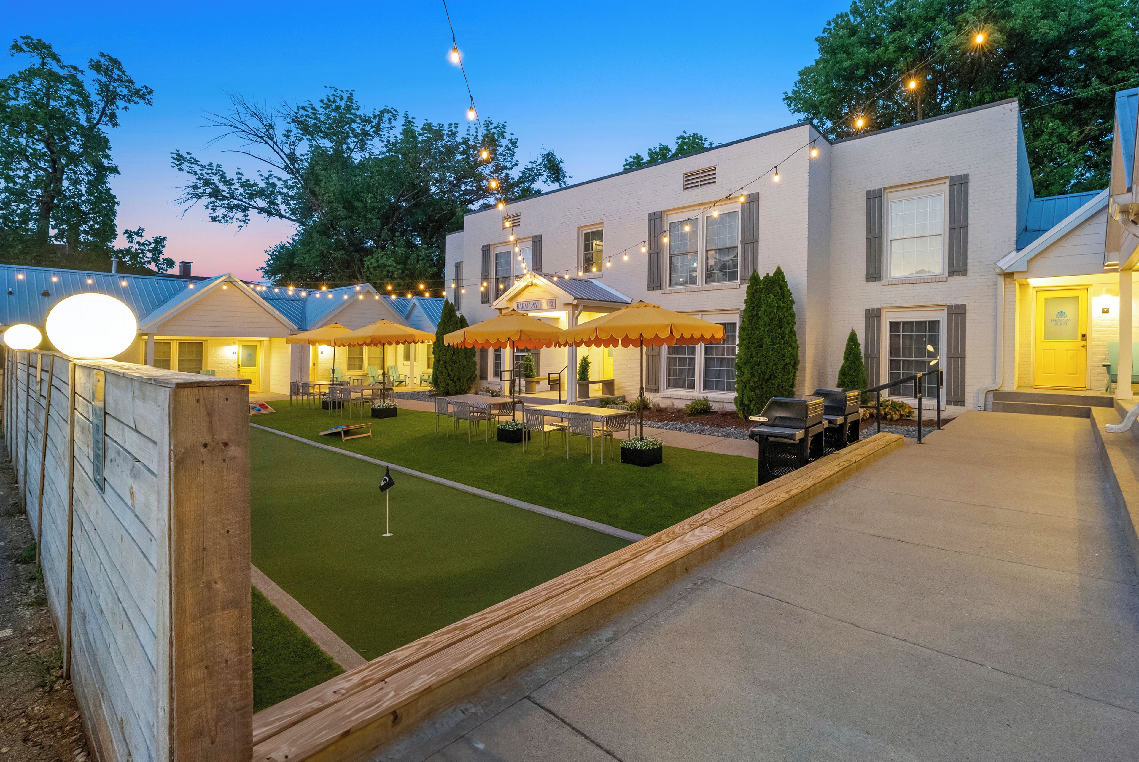 A well-lit outdoor patio area with string lights, a putting green, and outdoor seating.