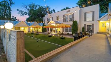 A well-lit outdoor patio area with string lights, a putting green, and outdoor seating.
