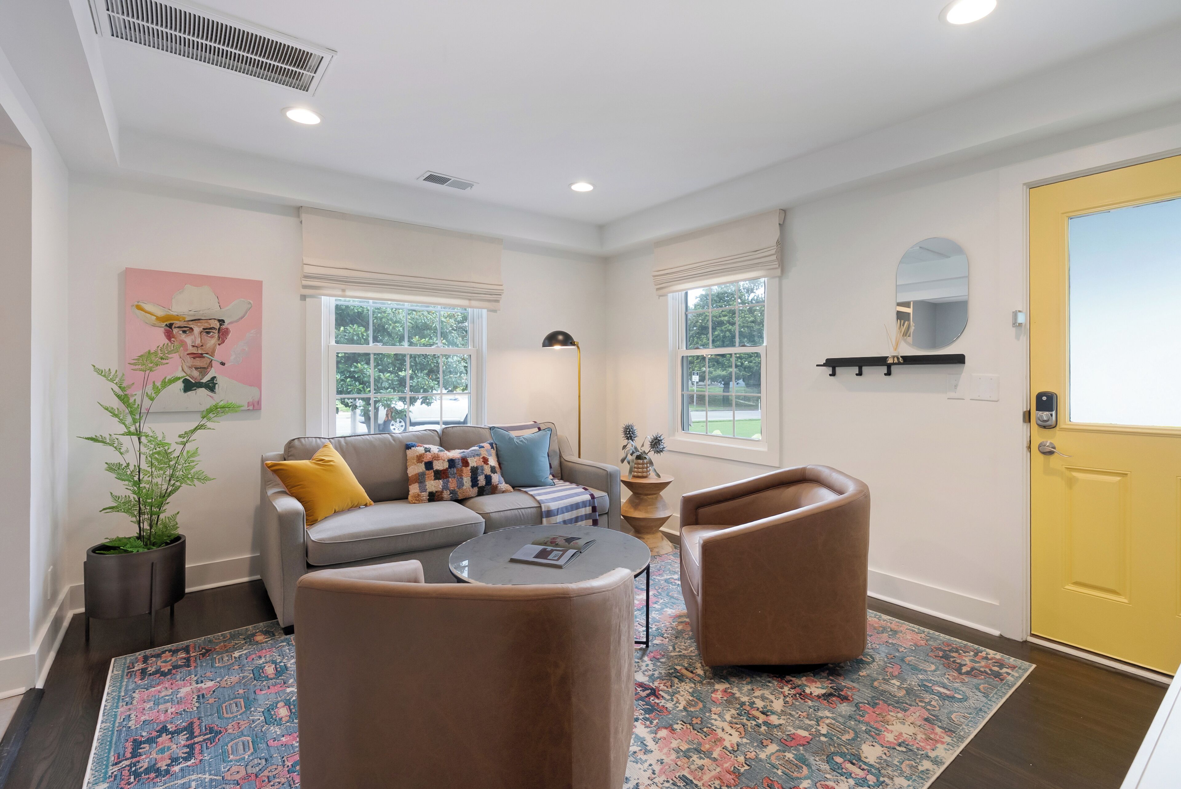 A living room with a sofa, armchairs, a coffee table, and a patterned rug.
