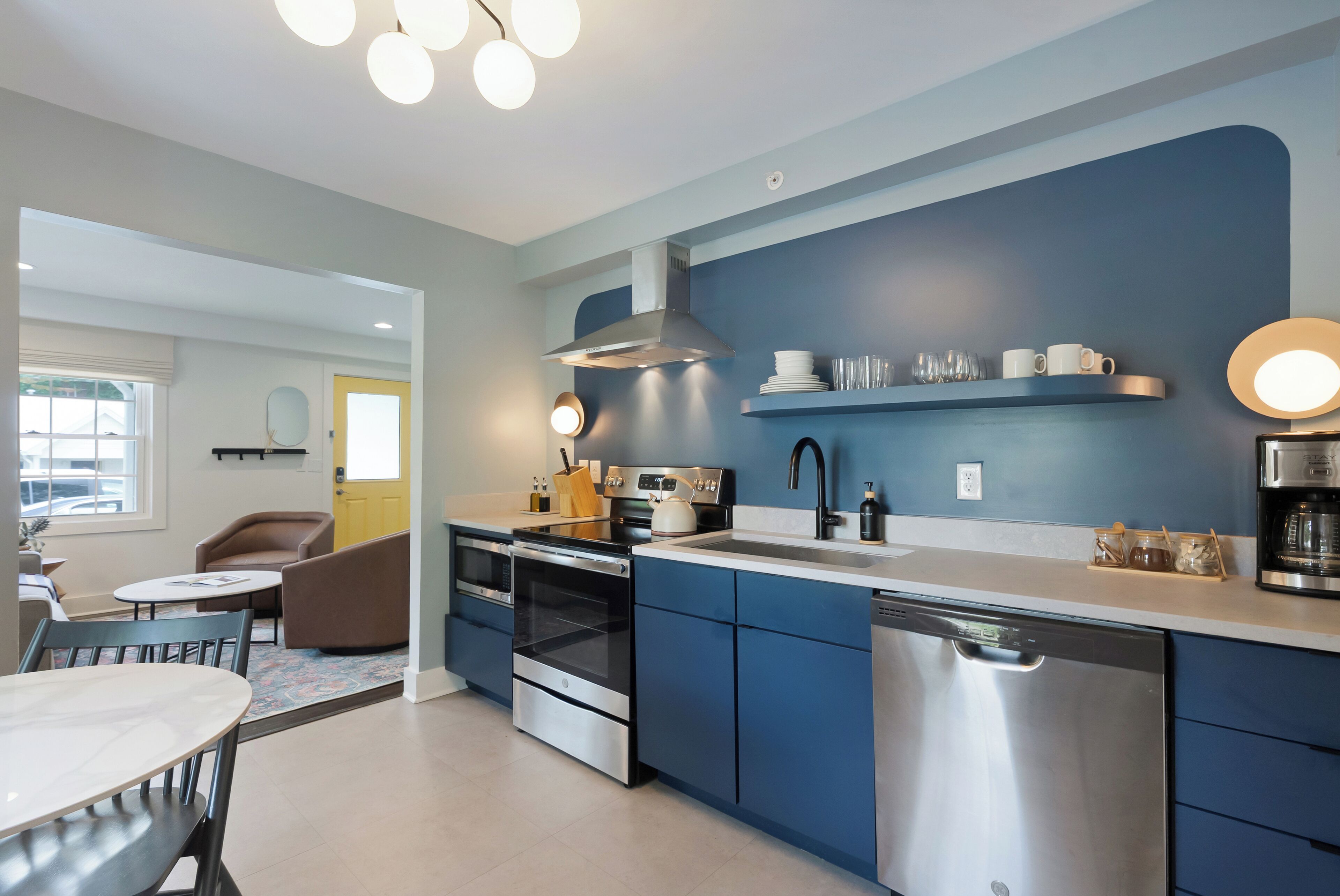 A modern kitchen with blue cabinets, stainless steel appliances, and a white countertop.