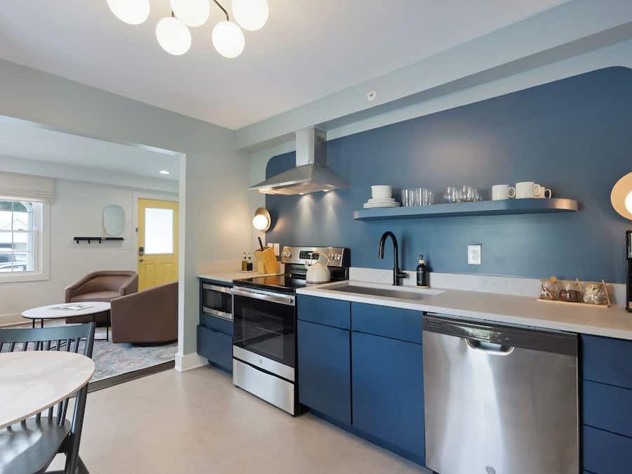 A modern kitchen with blue cabinets, stainless steel appliances, and a white countertop.