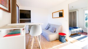Um espaço compacto com sofá, mesa de jantar, televisão e espelho.